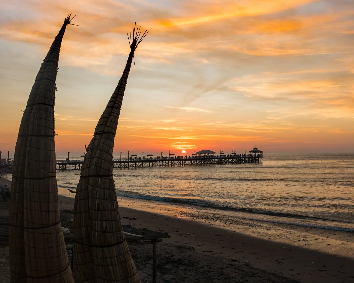 Atardecer en Huanchaco, Trujillo, con caballitos de totora y el muelle